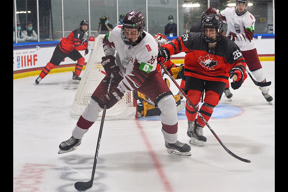 Team Canada and Moose Jaw Warriors defenceman Denton Mateychuk keeps an eye on a Latvia attacker in the corner.