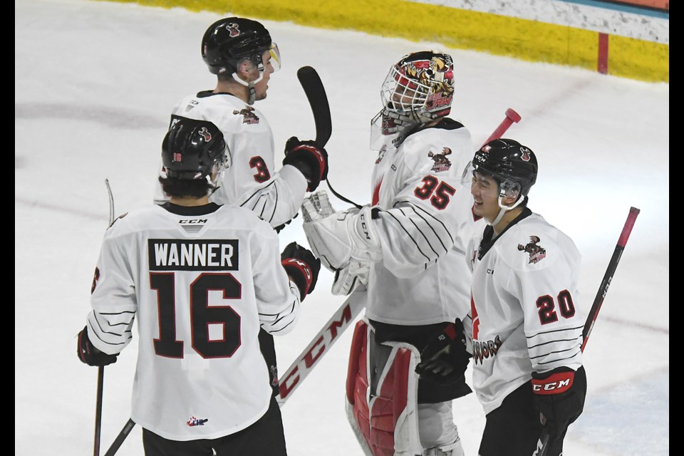 Defencemen Lucas Brenton (3) and Max Wanner join Thomas Tien in congratulating Carl Tetachuk on his second shutout of the season.