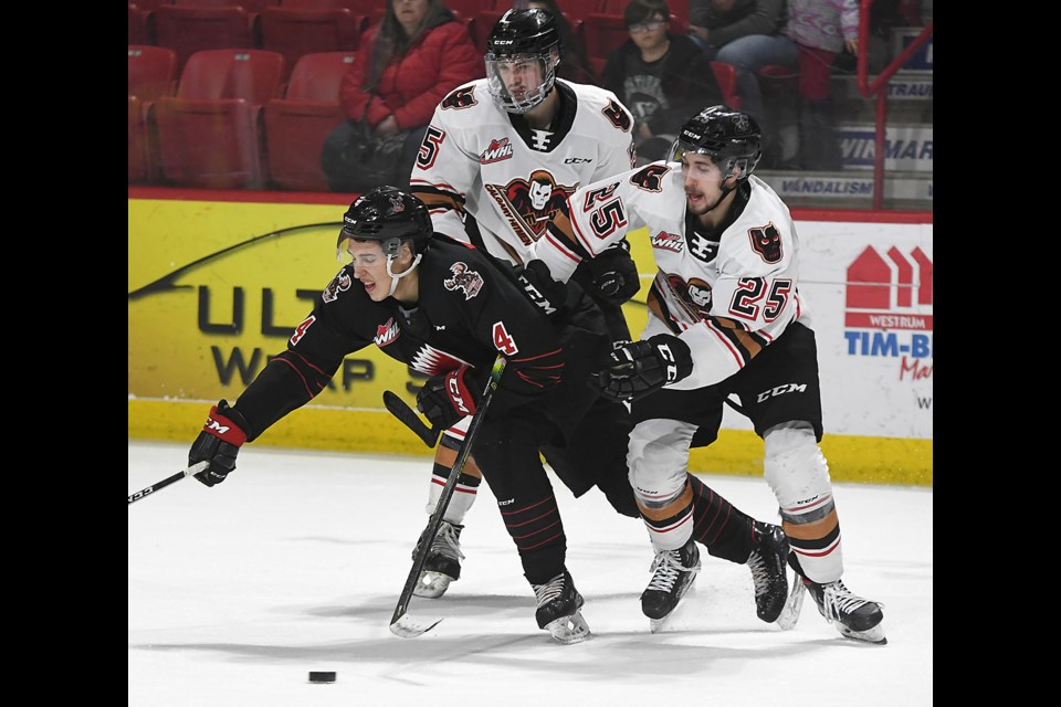 Warriors forward Eric Alarie battles with Calgary’s Blake Allan (25) and Jackson Van De Leest.