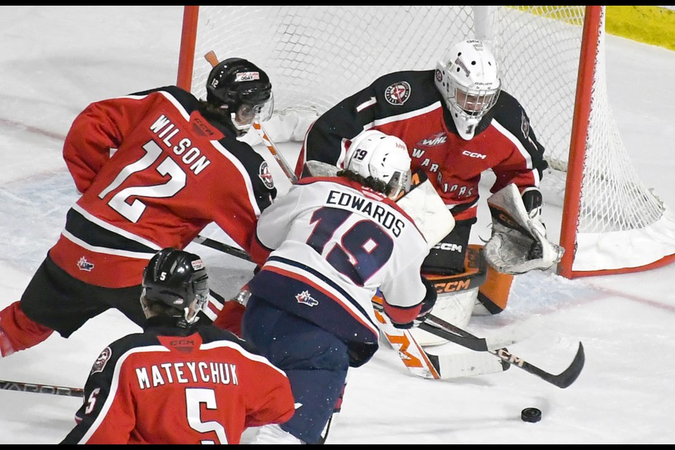 Warriors goaltender Evan May makes a save in close on Brayden Edwards as Cosmo Wilson covers the play.