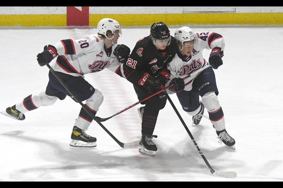 Warriors forward Tate Schofer attempts to fight through a pair of Regina Pats defenders