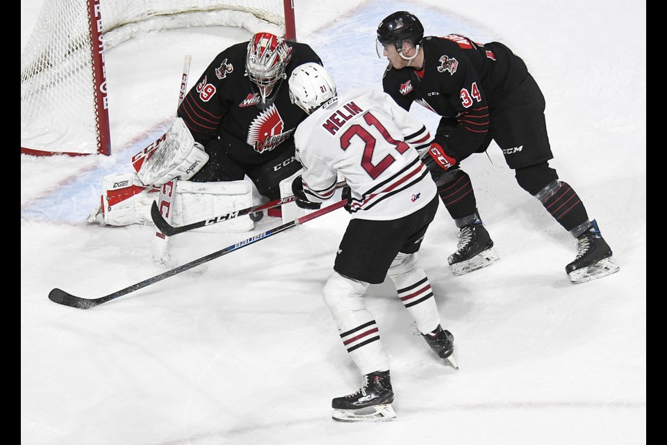 Moose Jaw Warriors goaltender Adam Evanoff stops Dalloon Melin in close as Cayde Augustine covers the play.