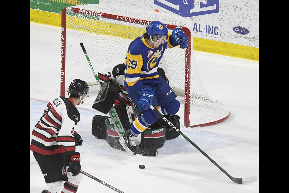 Saskatoon Blades forward Riley McKay leaps to get out of the way of a point shot in front of Warriors goaltender Boston Bilous.