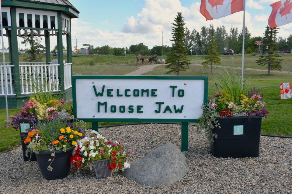 A view of Tourism Moose Jaw's entrance, featuring flowers donated by Windmill Greenhouses and Cornell Design & Landscaping. In the background, two bison sculptures by Bill Keen and a newly installed Red River cart highlight the growing Métis station.