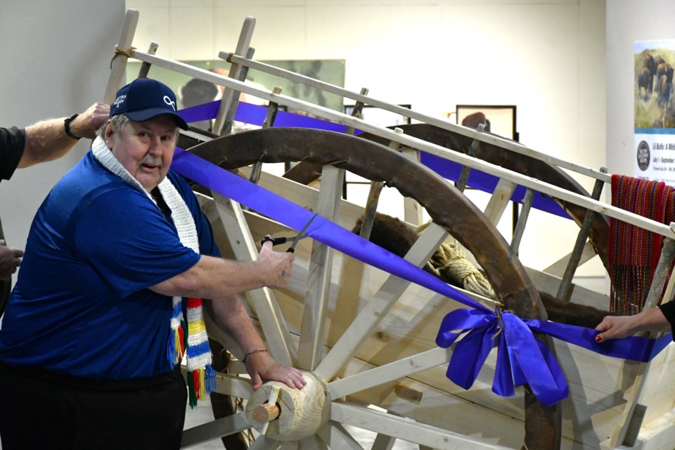 Darrell Hawman, president of the New Southern Plains Métis Local No. 160, cuts the ribbon during the official unveiling of the Red River cart exhibit at the Western Development Museum in Moose Jaw recently.
