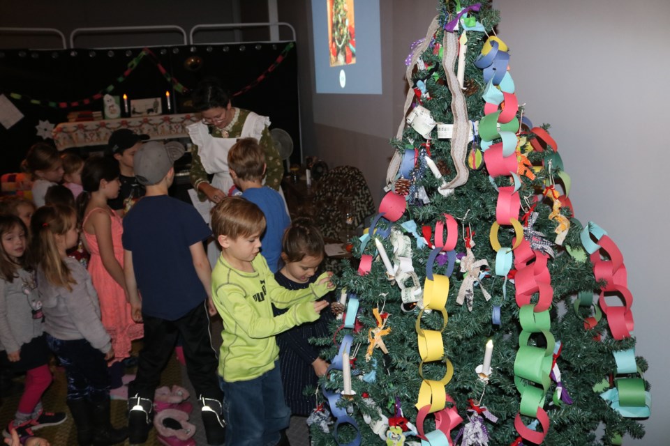 Children in the Christmas Long Ago program hang decoration on a Christmas tree at the Western Development Museum on Saturday. Photo by Shawn Slaght