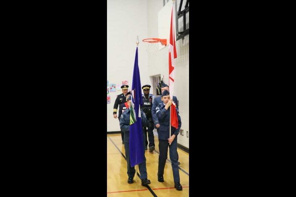 The colour party marches into the school gym for the Remembrance service.
