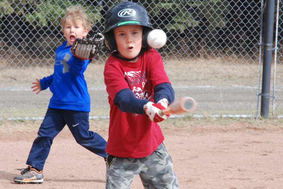 Ryder Chapman, 6, takes a swing while Waylon Jensen, 6, runs past in the background in anticipation of catching the ball for coach Shauna Bartholow, who was lobbing them pitches on Monday, May 3 during Sundre Minor Ball’s first practices of the season. All three diamonds behind the schools were being used, with coaches donning face coverings. However, as a result of tightened restrictions, practices have been put on hold for at least few weeks. 
Simon Ducatel/MVP Staff