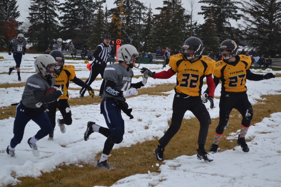Aidan Whitehead (10) of the Olds bantam Bulldogs blocks for teammate David Yanos as he heads upfield in a playoff game against Drumheller Oct. 22 at Normie Kwong Park.