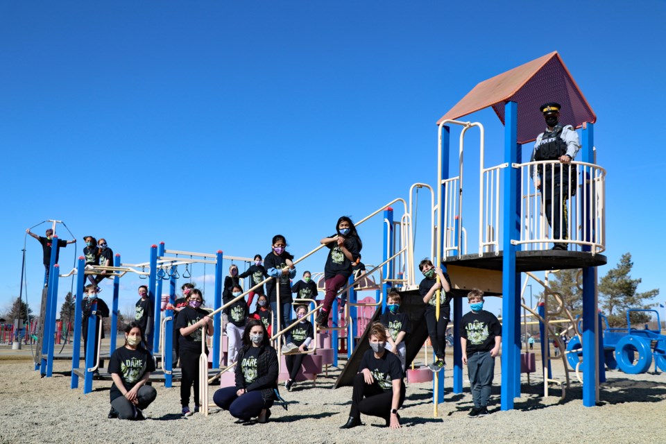 Almost two dozen Grade 5 students from the 2021 D.A.R.E. classes at St. Marguerite Bourgeoys Catholic School celebrate their graduation on March 23 with teachers and Innisfail RCMP Const. Craig Nelson, the detachment's community/school resource officer (upper right). It was the D.A.R.E. program's first local COVID-era graduation. Johnnie Bachusky/MVP Staff

