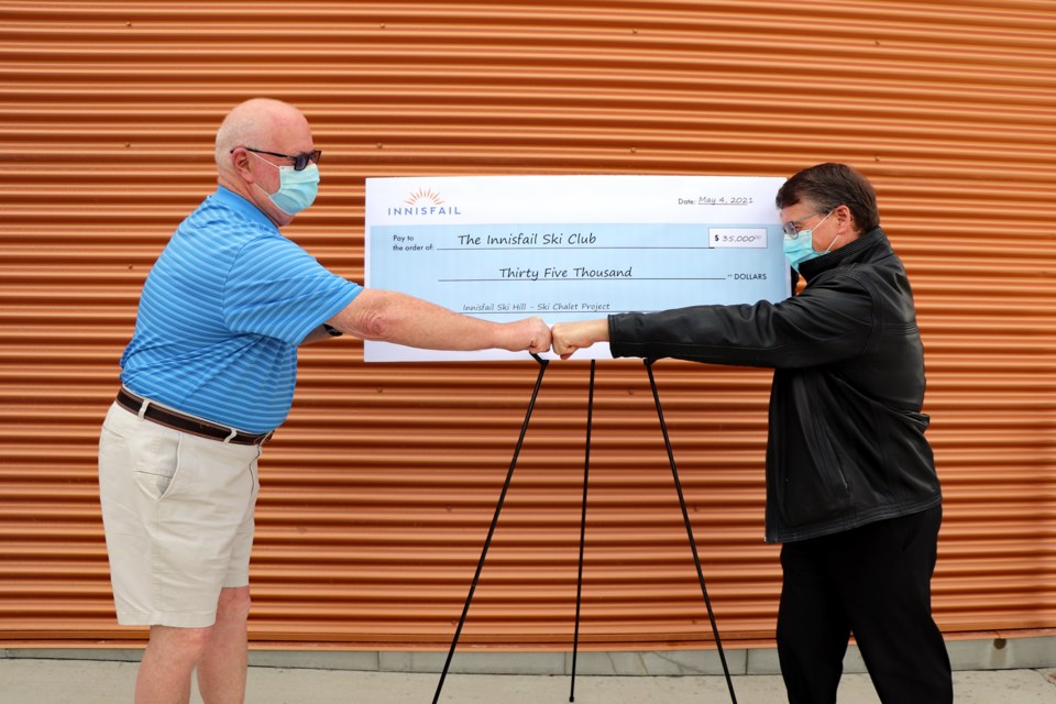 Mayor Jim Romane, left, and Brent Jackson, president of the Innisfail Ski Hill, do a COVID-19 handshake following the presentation of a Town of Innisfail cheque of $35,000 to the ski hill. Last month town council approved the funds to assist the club in the building of the new $385,000 chalet, which is now about 90 per cent complete. Johnnie Bachusky/MVP Staff