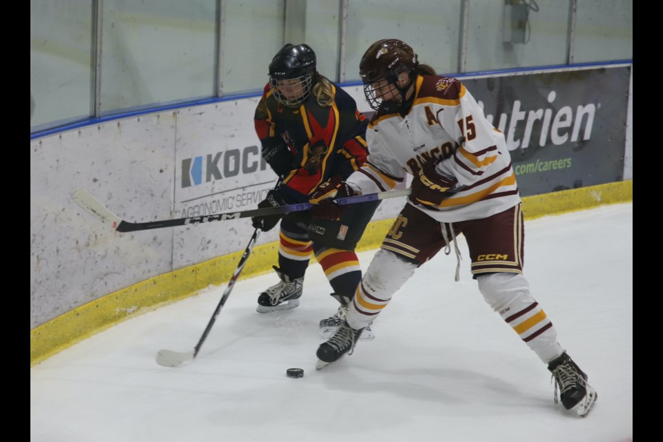 Tessa Knisley of the Olds College Broncos battles for the puck against a member of the Olds and Area First Responders.