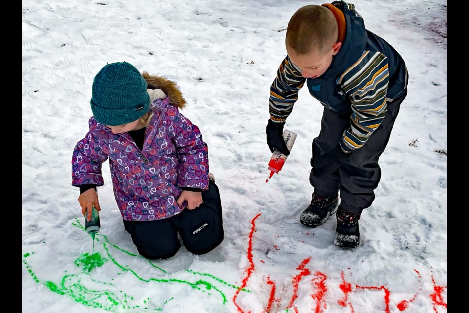 Four-year-old Ariya Anderson, left, and Chris Franken, 5, draw in the snow with coloured water at the Bowden Family Winter Fun event on Feb. 11 beside the Olde Library Community Centre. The event featured games, hot chocolate and roasting s'mores treats over an outdoor fire.