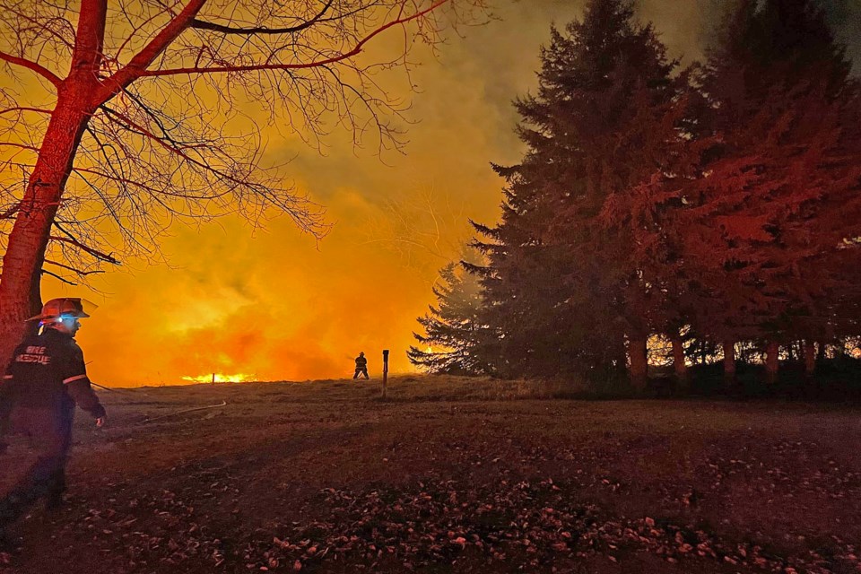 A firefighter in the distance battles a large ground fire in a field on the far west side of Innisfail early in the morning on April 10 while another heads out to help. 
Facebook photo