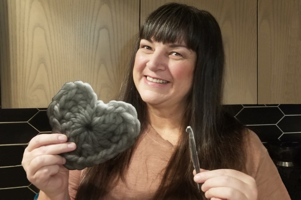 Calgary artist Karen Scarlett with a crocheted heart. Scarlett, who was raised in Innisfail, is about to launch the Crochet BOMB Project; a new public art initiative that will begin with the artistic touches from local seniors. 
Photo by Doug Symington