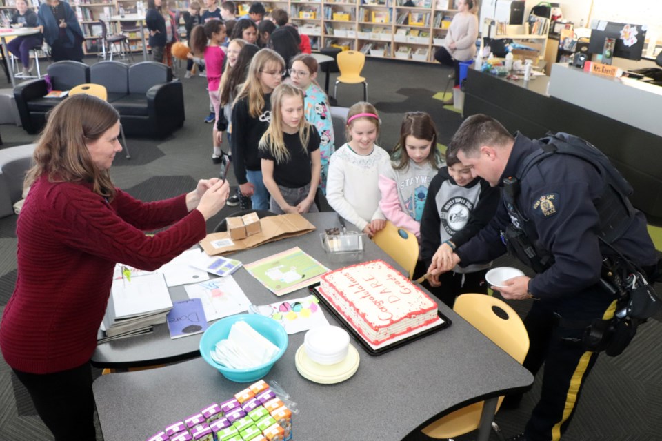 Innisfail RCMP Const. Craig Nelson, the detachment's community schools resource officer, cuts the cake for the Grade 5 students at St. Marguerite Bourgeoys Catholic School who celebrated their D.A.R.E. graduation on March 8. Johnnie Bachusky/MVP Staff