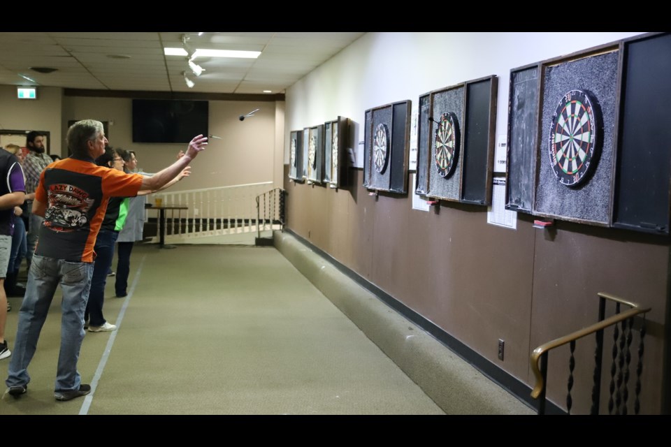 Bill De boer, foreground, and other competitors throw darts during a one-day tournament held April 1 in the dart room of the Royal Canadian Legion Branch #105. The purpose of the tournament was to raise funds for Olds & District Special Olympics.