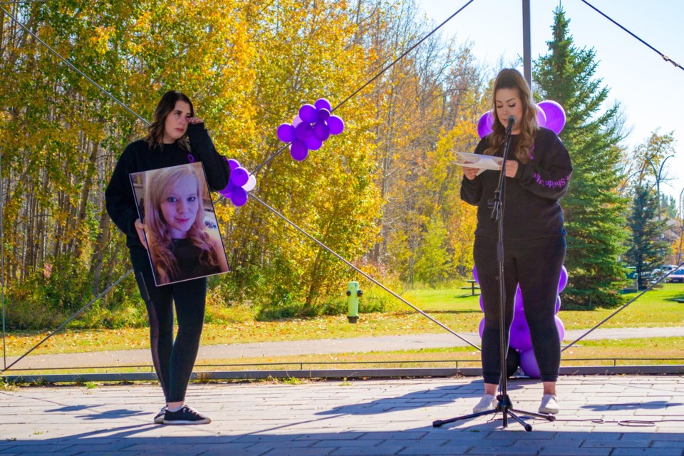 Bailey Whalen (left) holds a portrait of late sister Kirsten Gardner while sibling Ashley Christoffersen delivers a powerful presentation during the 2nd annual Innisfail March Against Domestic Violence and Intimate Partner Abuse at Centennial Park on Oct. 2. Photo by Candice Hughes