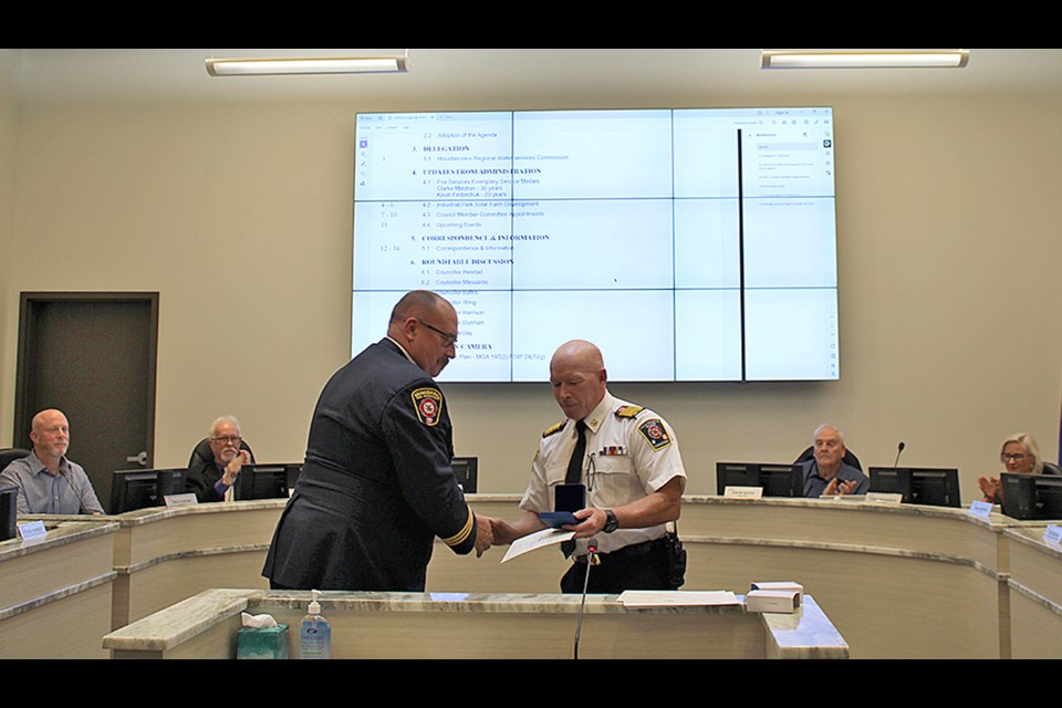 Clark Maldaner, assistant deputy chief of the Innisfail Fire Department, left, receives recognition from local fire chief Gary Leith at town council on Oct. 16 for earning the 30-year Fire Services Exemplary Service Medal. Town of Innisfail photo