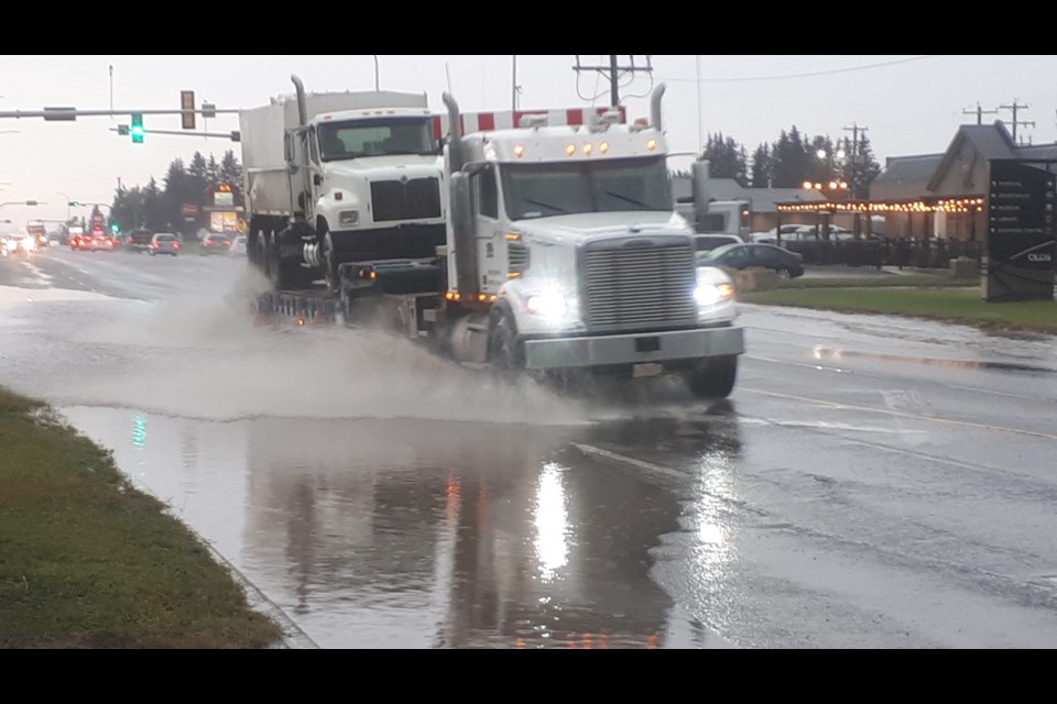 Water sprays from big trucks as they head up Highway 27 near 50th Avenue just after the July 10 rain storm.