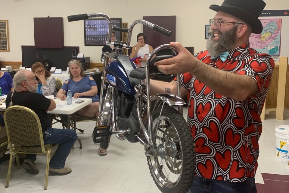 Kelson Bastien was among several volunteers presenting the items up for bid, including this refurbished and unique child’s bike fashioned to resemble a motorcycle that was stripped and remade by Blaine and Kim Free with some assistance from Ryan Paron and Fred Tyler that ended up going for $200. Simon Ducatel/MVP Staff