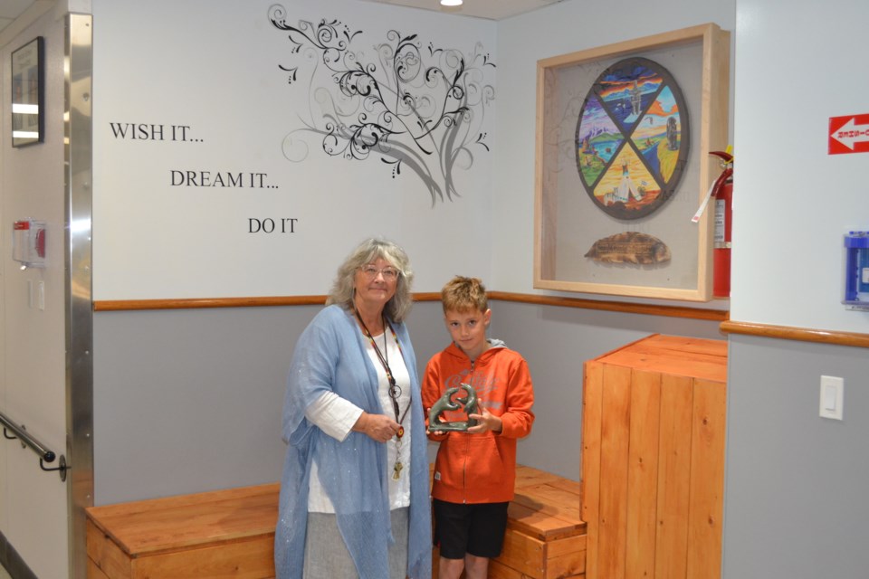 Ten-year-old Horizon School student Sawyer Strocher, right, receives a sculpture to commemorate truth and reconciliation from project co-organizer Bev Toews.