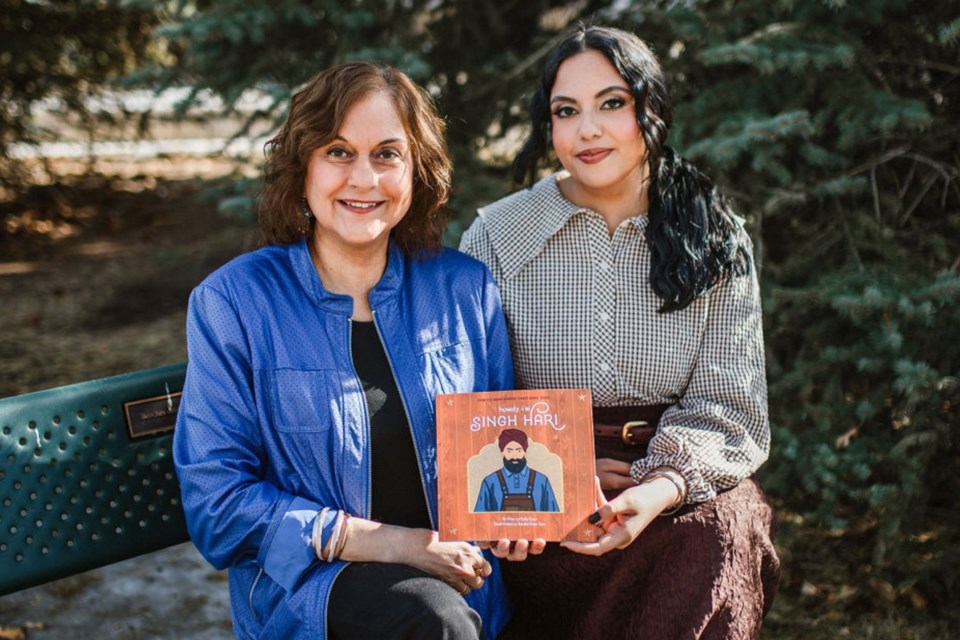 Author Kelly Kaur, left, and illustrator Ravina Toor hold a copy of Howdy, I’m Singh Hari at Singh Hari Park in Calgary. 
Photo courtesy of Grey Wall Design Studio