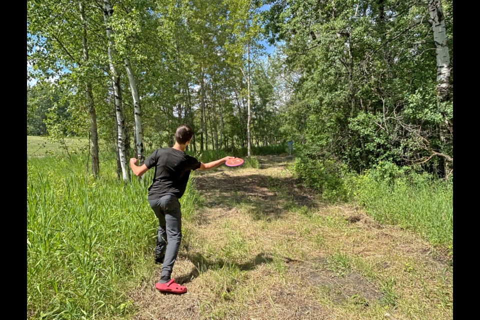 A young disc golfer throws an opening shot on June 26 at the 14th hole on the new back nine at Centennial Park's Innisfail Kinsmen Disc Golf Park. Johnnire Bachusky/MVP Staff