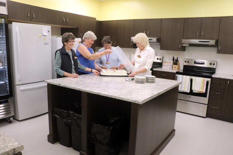 From left to right,  Jean Bennett, a member of the renovation committee; Cheryl Scheie, a member of the Innisfail Senior Drop-In Society; society member Marian Breeze; and Gail Tetzlaff, chairperson of the renovation committee, prepare a birthday cake on the island in the seniors drop-in centre's new kitchen. Johnnie Bachusky/MVP Staff