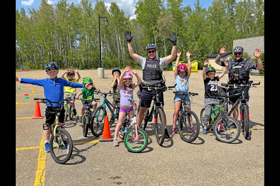 Innisfail RCMP Const. Craig Nelson, lead organizer of the 5th annual Innisfail RCMP Bike Rodeo (centre), and Innisfail Senior Peace Officer Sgt. Derek Radatzke (right), celebrate success with young bike riders at the 5th annual Innisfail RCMP Bike Rodeo on May 24 in the parking lot of the Innisfail Library/Learning Centre. Johnnie Bachusky/MVP Staff