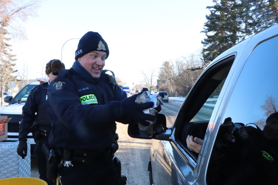 Innisfail RCMP Const. Craig Nelson offers Purina pet treats to an Innisfailian stopping at the 26th annual Innisfail RCMP Charity Check Stop on Dec. 3. Purina and many other local businesses strongly supported the event with donations and support to volunteers. 
Johnnie Bachusky/MVP Staff
