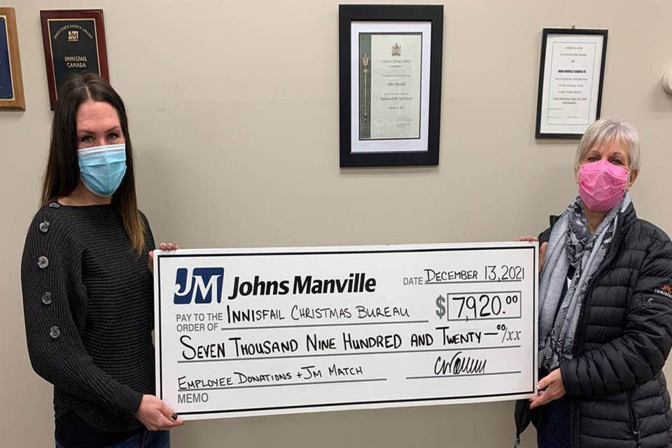 Lynn Holinski, chair of the Innisfail Christmas Bureau, right, receives a cheque for $7,920 from Crystal Workun, the plant manager at Johns Manville. Submitted photo