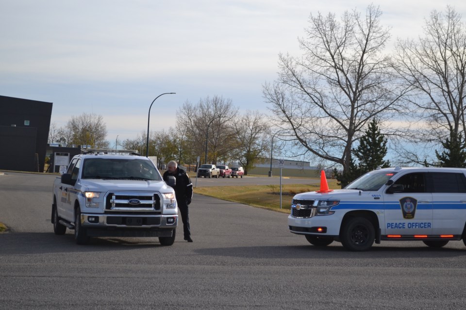 Olds senior community peace officer Paul Wright confers with RCMP at the entrance to Olds High School during a lockdown Oct. 28.
