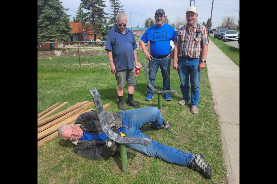 Central Alberta Men's Shed (Innisfail) member Brad Watson is on the ground reparing one of three benches the group worked on this month by Autumn Grove. Watching Watson's dedication are work colleagues, from left to right, George Matthie, Dave Thomas and Henry Beekman. Submitted photo
