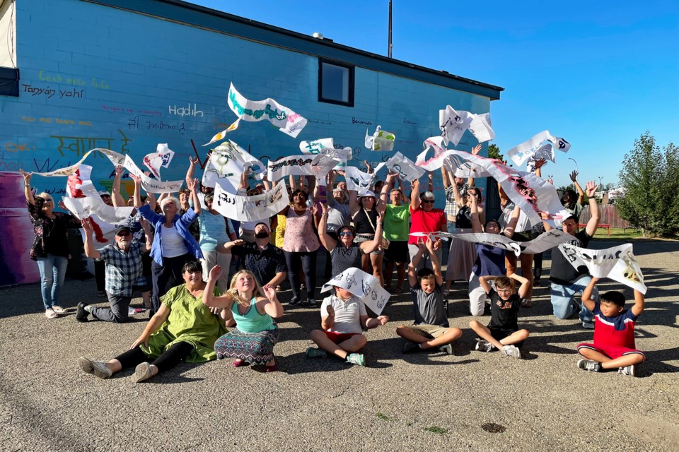 Up to 40 volunteers for Innisfail's downtown Welcome Mural on the south wall of The Cottage Cottage throw their welcome stencils in the air on Aug. 18th to celebrate the conclusion of the month-long community project. The stencils were in dozens of different languages to honour the inclusivity of the town and to welcome all current and new citizens of all cultural and ethnic backgrounds. Johnnie Bachusky/MVP Staff
