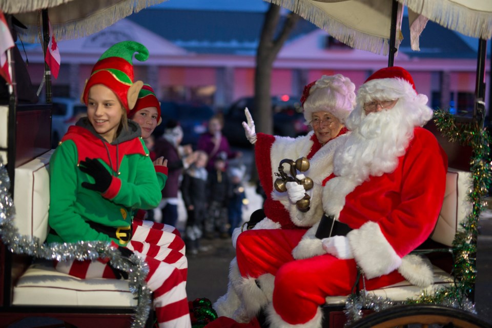 Santa Claus and Mrs. Claus wave as they make their way along the Olds Fashioned Christmas parade route on Nov. 23. 
Noel West/MVP Staff