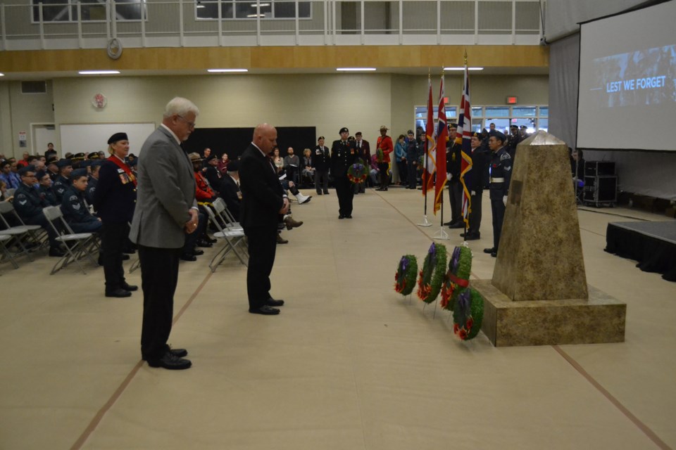 Sgt. At Arms Leslie Manchur, far left, watches as Mountain View County councillor and Rural Municipalities of Alberta president Al Kemmere, left, and Olds mayor Michael Muzychka pay tribute after laying wreaths at the cenotaph during Olds Remembrance Day services Monday at the Community Learning Campus. Doug Collie/MVP Staff
