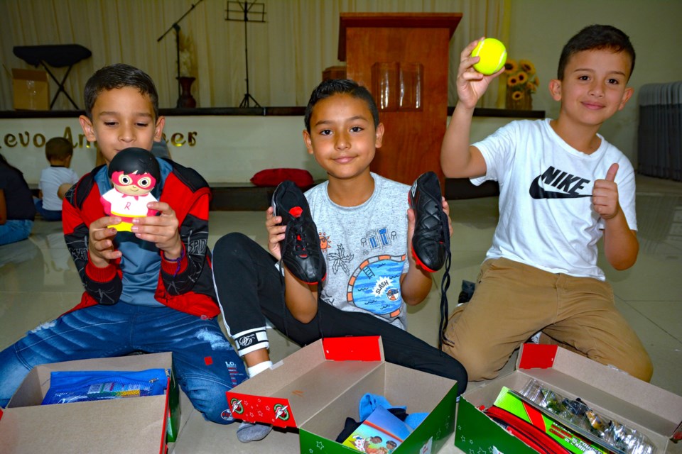 A trio of children in Costa Rica play with their new doll, ball and shoes aftrer opening their shoeboxes from Operation Christmas Child. Photo by Frank King