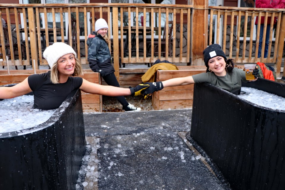 Claire Bond (left) and Peyton Sunstrum hold hands and smile during their five-minute polar plunge outside Dark Woods Brewing along Innisfail's Main Street for the 3rd Annual Dark Woods Polar Plunge on March 15. The well-attended event was a fundraiser for the town's Helping Hand Fund. Johnnie Bachusky/MVP Staff