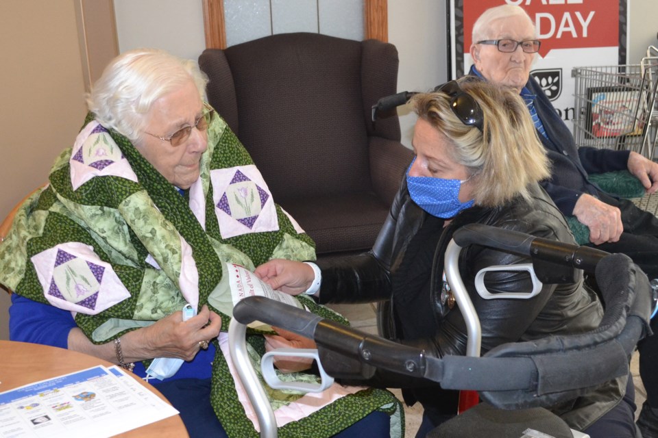 Quilts of Valour-Canada Central Alberta representative Nicole Langlois reads out what's written on a quilt she wrapped around Second World War veteran Betty Reader.