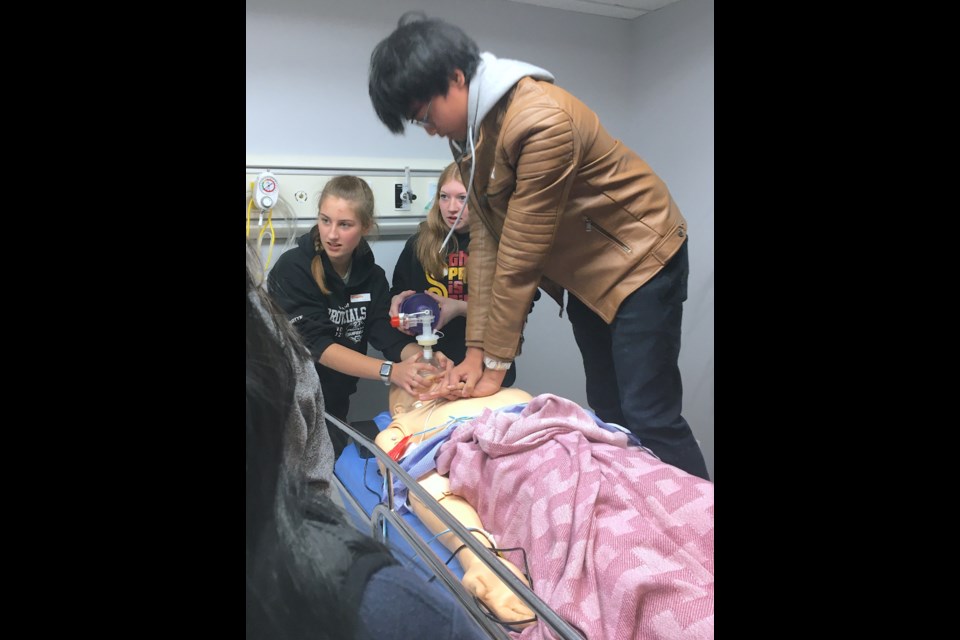 Sundre High School Grade 11 student Henrey Catubig practises chest compressions on Earl – a sophisticated roughly $8,000 medical training dummy that can simulate a pulse, breathing, seizures and even screams – while Grade 10 students Brooklyn May, left, and McKenzie Lorimer intently keep an eye on the replica patient's heart monitor as they provide air flow. The students were among a group of about 50 who on March 21 came from Sundre, Caroline as well as Cremona to participate in a nurse skills day hosted at the new eSIM lab located immediately adjacent to and connected with the Sundre Fire Hall.  
Simon Ducatel/MVP Staff