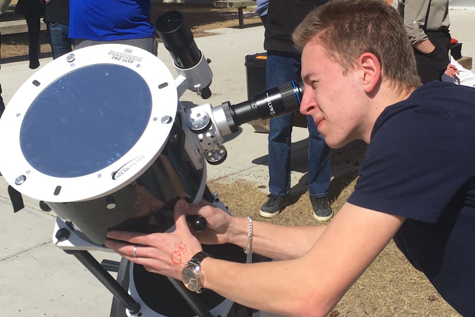 Dane Roberts, a Grade 11 student at Sundre High School and a hobby astronomer who enjoys the opportunity to keep an eye in the sky for celestial events, helped line up a telescope fitted with a special solar filter set up by science teacher Kris Kowaliuk so that interested students could catch a glimpse of Monday’s partial solar eclipse.
Simon Ducatel/MVP Staff