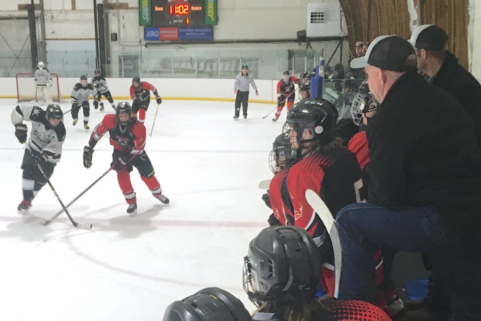 Coach Jason Martyn, to the right leaning on his left knee, watches a play come up the ice toward the Huskies’ zone on Friday, Jan. 26 during the opening game against the Taber Oil Kings. 
Simon Ducatel/MVP Staff