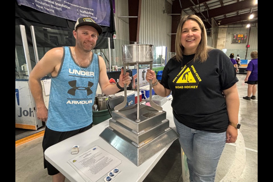 Andrew Thompson and Nicole Pillman, committee members of the Helping Hand Fund Innisfail, stand proudly beside the championship trophy for the 28th Annual Dean Turnquist Spring Fever Road Hockey Tournament that was held May 3 at the Innisfail Twin Arena. Johnnie Bachusky/MVP Staff