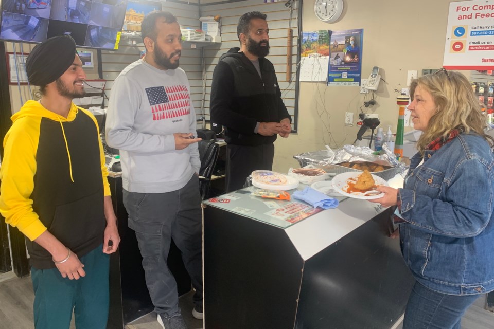 Sundre Car Wash co-owners Harry Singh, middle, and Kulwant Sarai, right, with attendant Arsh Singh chat on Wednesday, April 16 with Sundre resident Shelley Kohut, who had come in to offer a donation to replace the vandalized sign that by then had already been cleaned up. “I wanted them to know they were supported,” said Kohut, who didn’t pass up the offer to enjoy a samosa, adding she was “horrified” by what had been done to the sign that welcomes people to town in both English and Punjabi.  
Simon Ducatel/MVP Staff