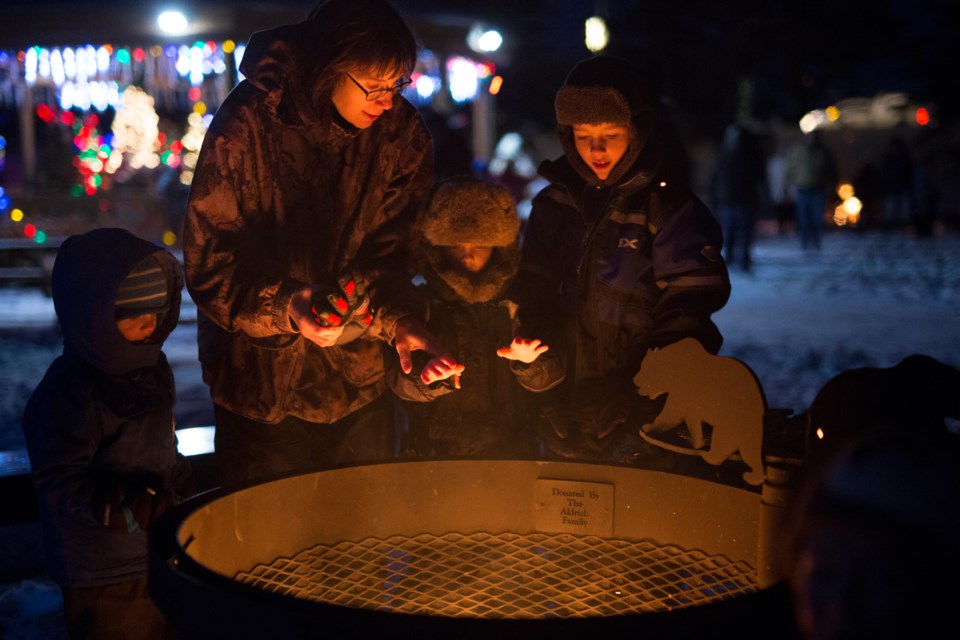 A family warms themselves at a fire at the Greenwood Campground gazebo during Sundre Snow Fest on Nov. 29. Noel West/MVP Staff