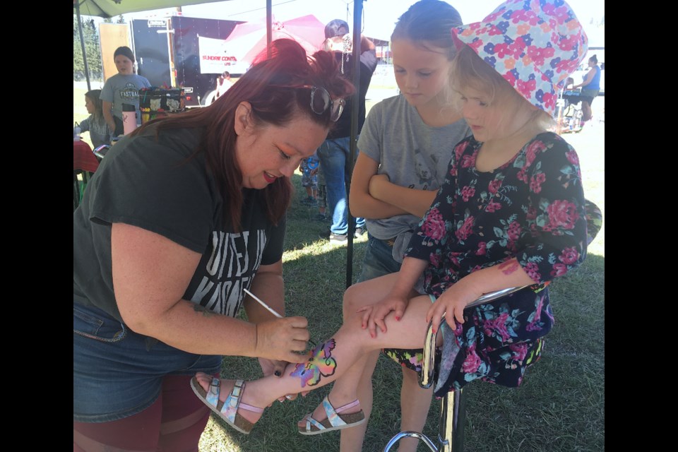 STEADY HANDS – Cynthia Spurrier applies her practised and steady artist’s hands as she paints a flower with butterflies while recipient Priya Allan, 5, attentively watches alongside curious onlooker Sadie Ouderkirk, 10. 
Simon Ducatel/MVP Staff