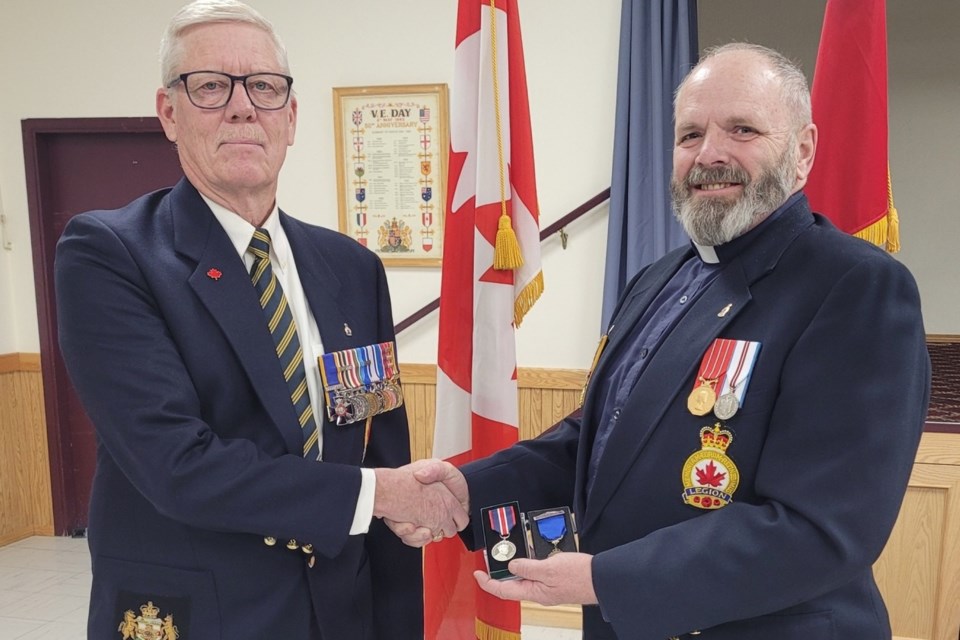 Dick Cruickshank, left, the executive member of the Royal Canadian Legion Branch #223 in Sundre who oversees honours and awards, recently presented outgoing president Rev. Todd MacDonald with the King Charles III Coronation medal at the local hall. Submitted photo