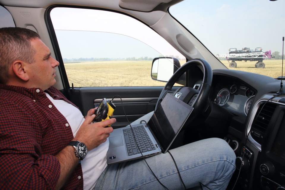 Independent contractor and precision ag technologist at Olds College Yevgen Mykhaylichenko remotely calibrates a robotic sprayer on an Olds College field.