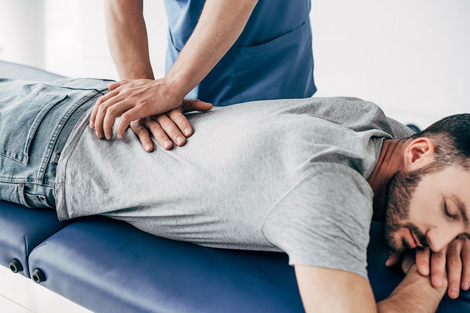 chiropractor-massaging-back-of-man-on-massage-tabl-2022-12-16-17-37-58-utc